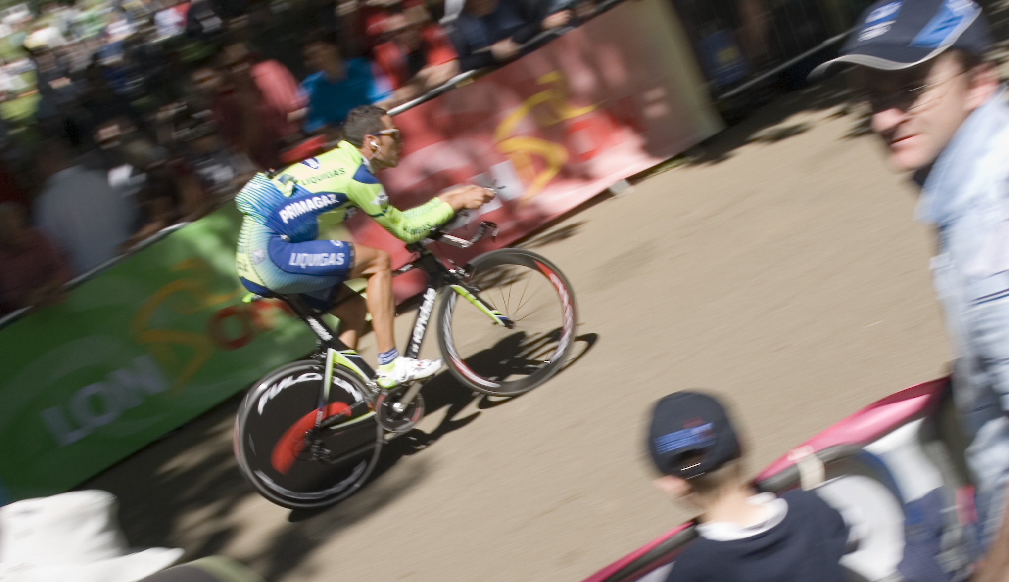 a cyclist in full uniform speeds by an audience