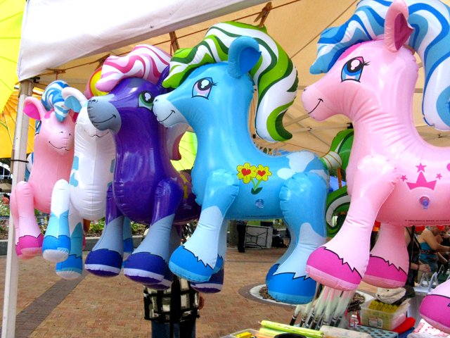 several inflatable toy horse rides stand under a tent