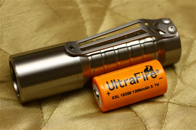 an orange battery and charger on a bed