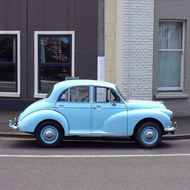 a blue classic car parked on the side of a street