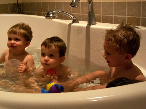 three children playing in the bathtub of the bathroom