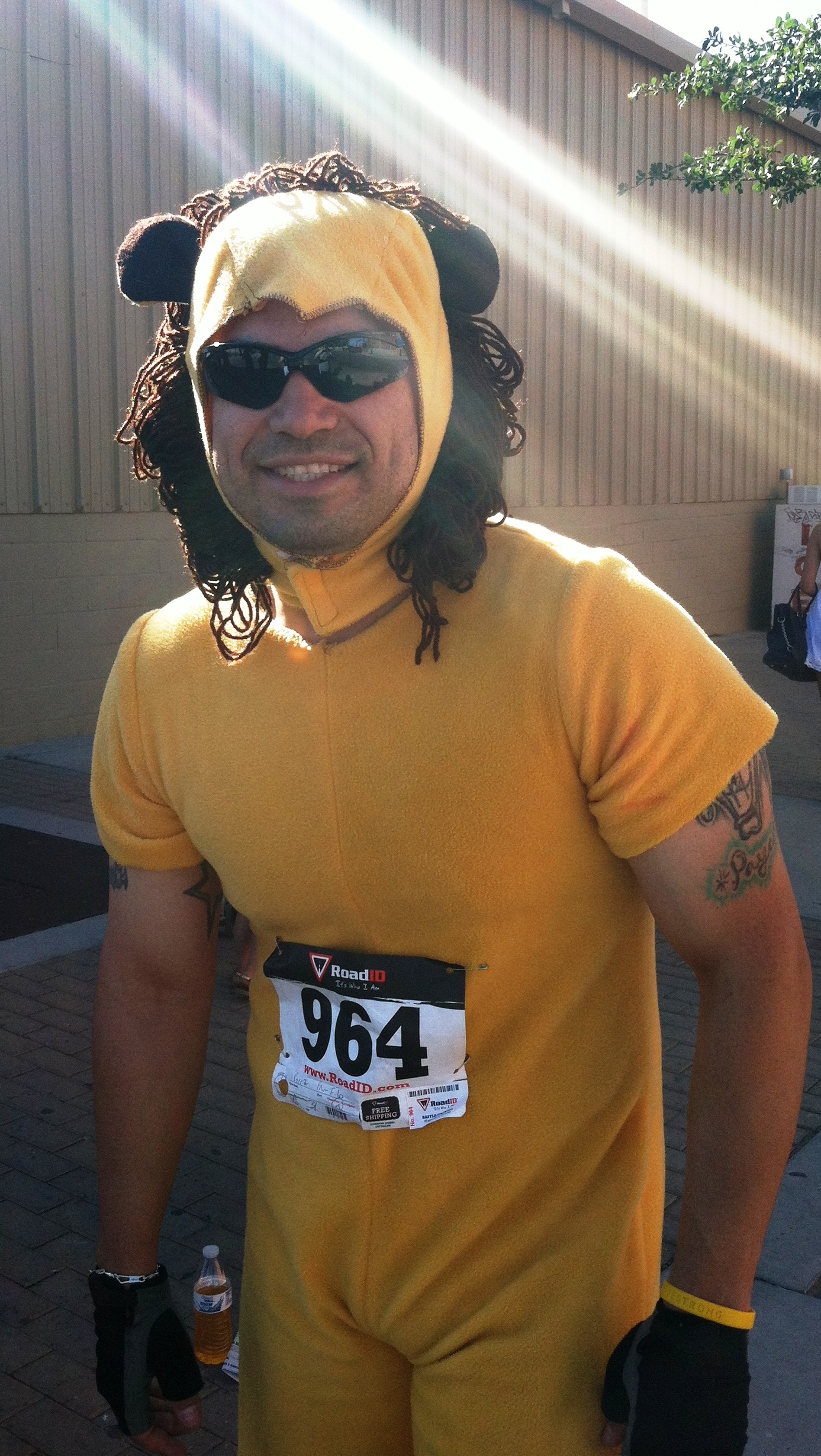 a man wearing a yellow shirt and a hat smiles at the camera