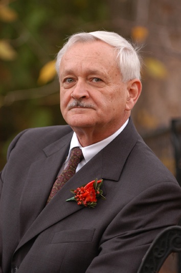 older gentleman in grey jacket and tie with flower