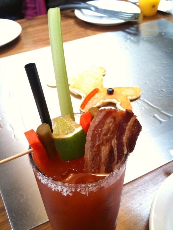 a tall drink has bacon, fruit, and apple slices on it