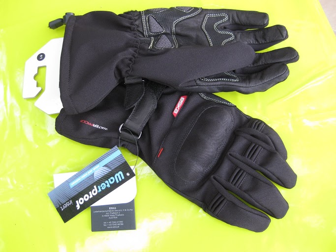 a pair of black motorcycle gloves, sitting on a reflective surface