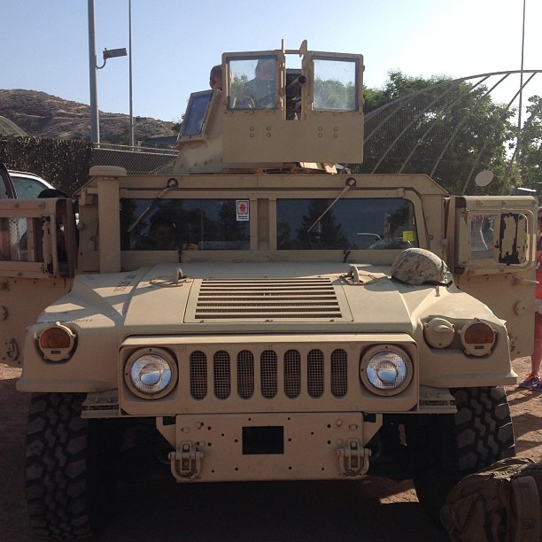 an army truck is parked outside on a dirt lot