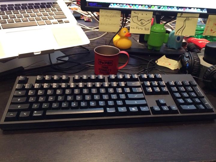 a keyboard with two coffee cups next to it on a desk