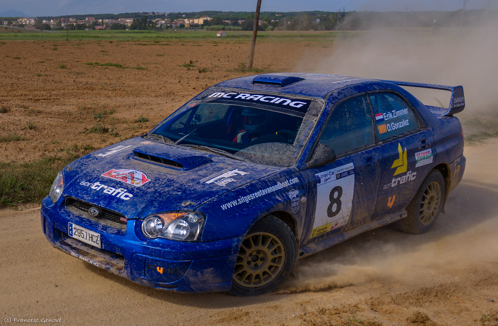 a blue sub car drives on dirt road during an outdoor event