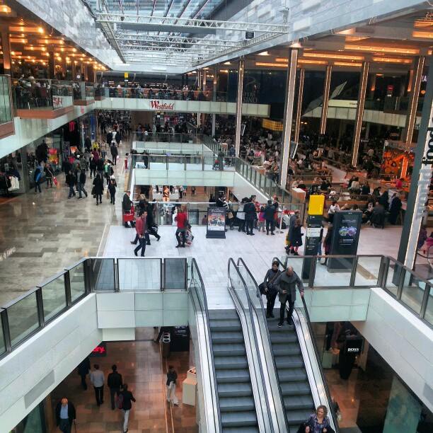 people walking through an indoor mall filled with escalators