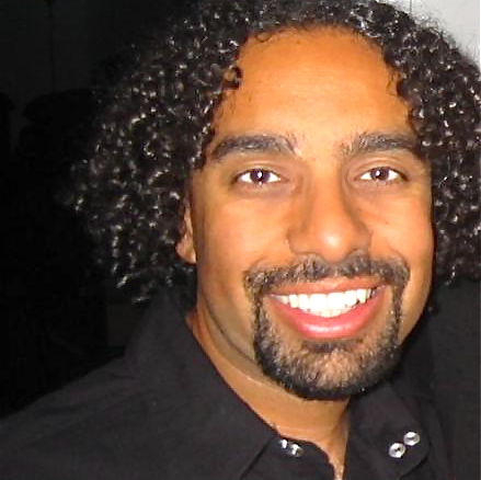 a smiling man with long curly hair and beard
