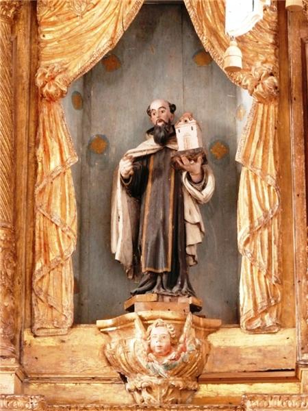 statue of st basil holding a book in front of a golden wall