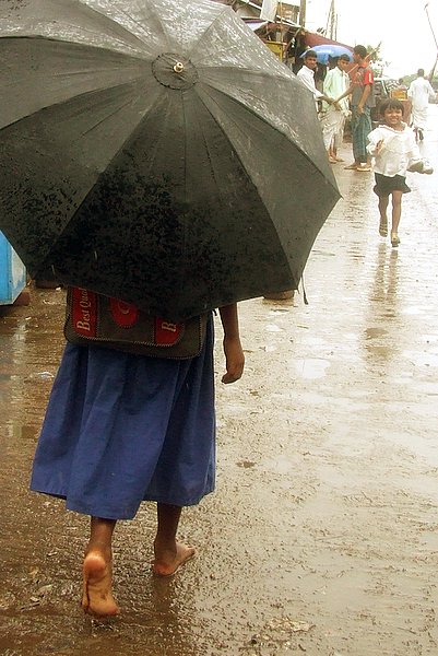 a person that is walking on a rainy sidewalk with a umbrella