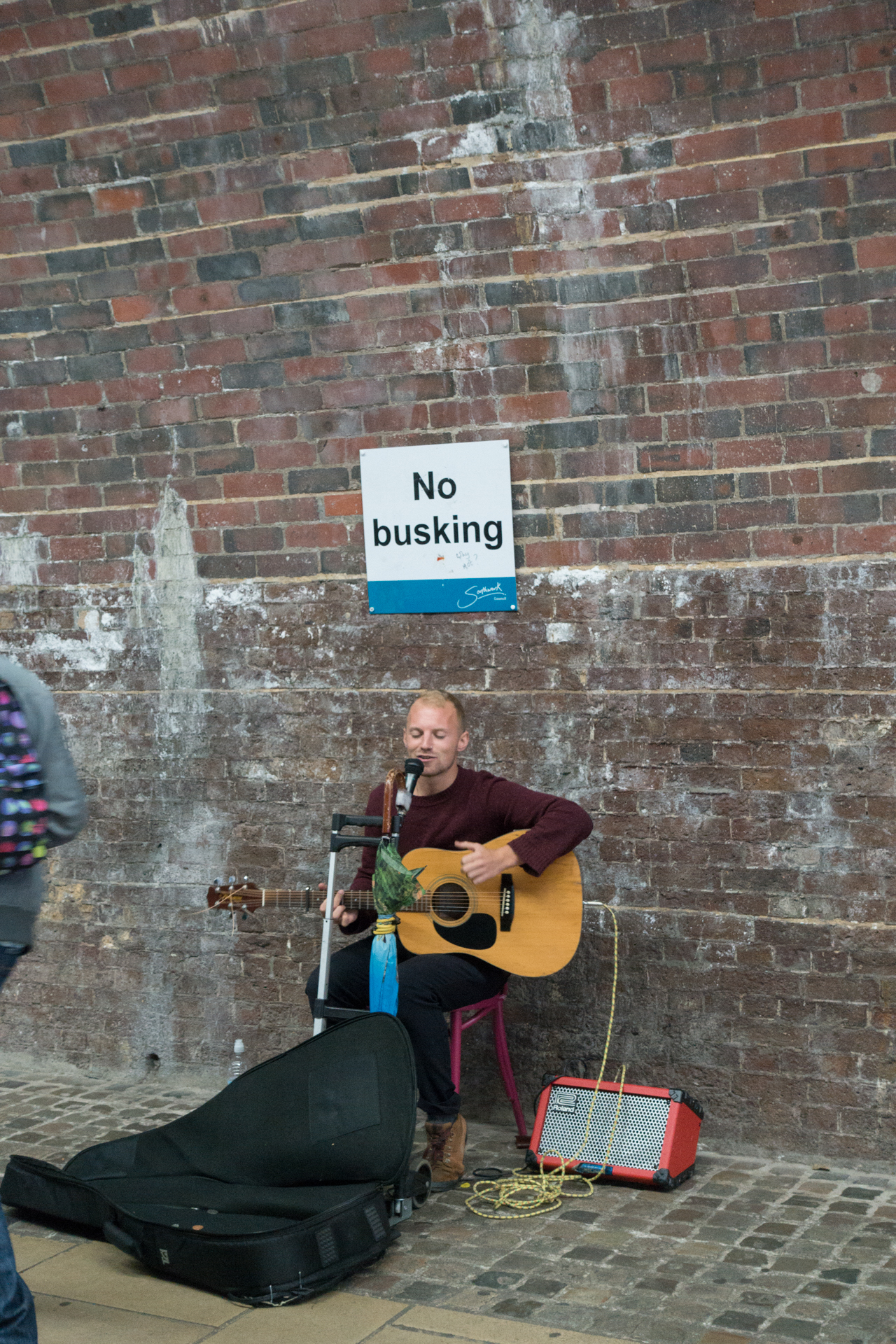 a man is playing an acoustic guitar on the sidewalk