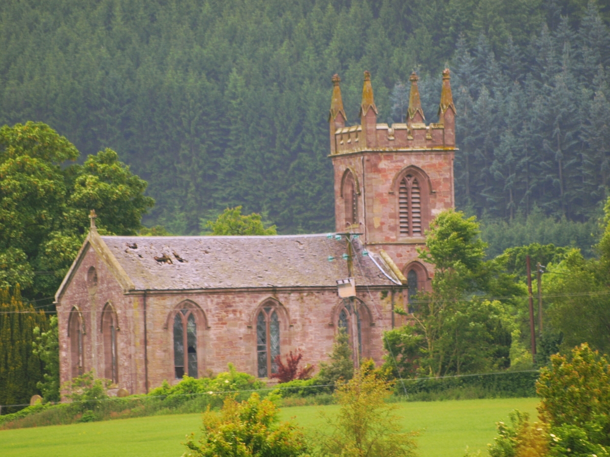 an old church sitting on the side of a lush green field