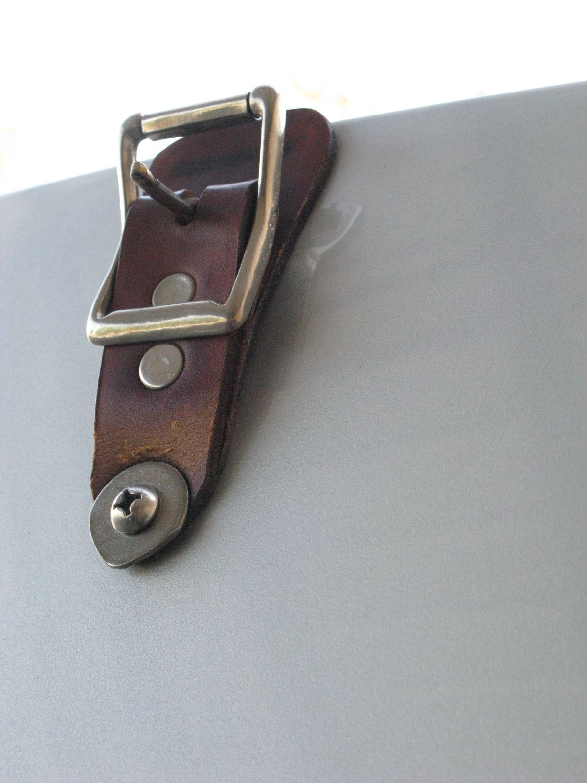 a brown leather belt sitting on a silver surface