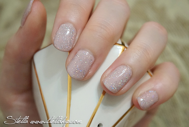 a hand holding a beige manicure with gold flakes