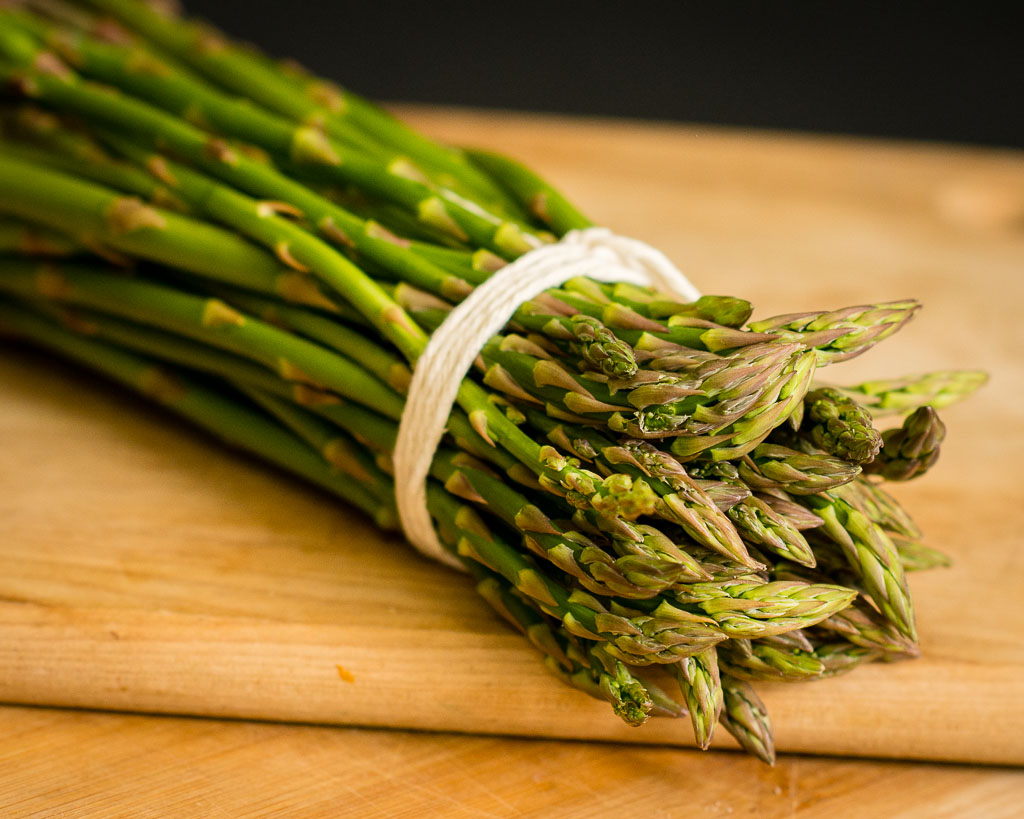 a bunch of asparagus is tied up on a wooden board