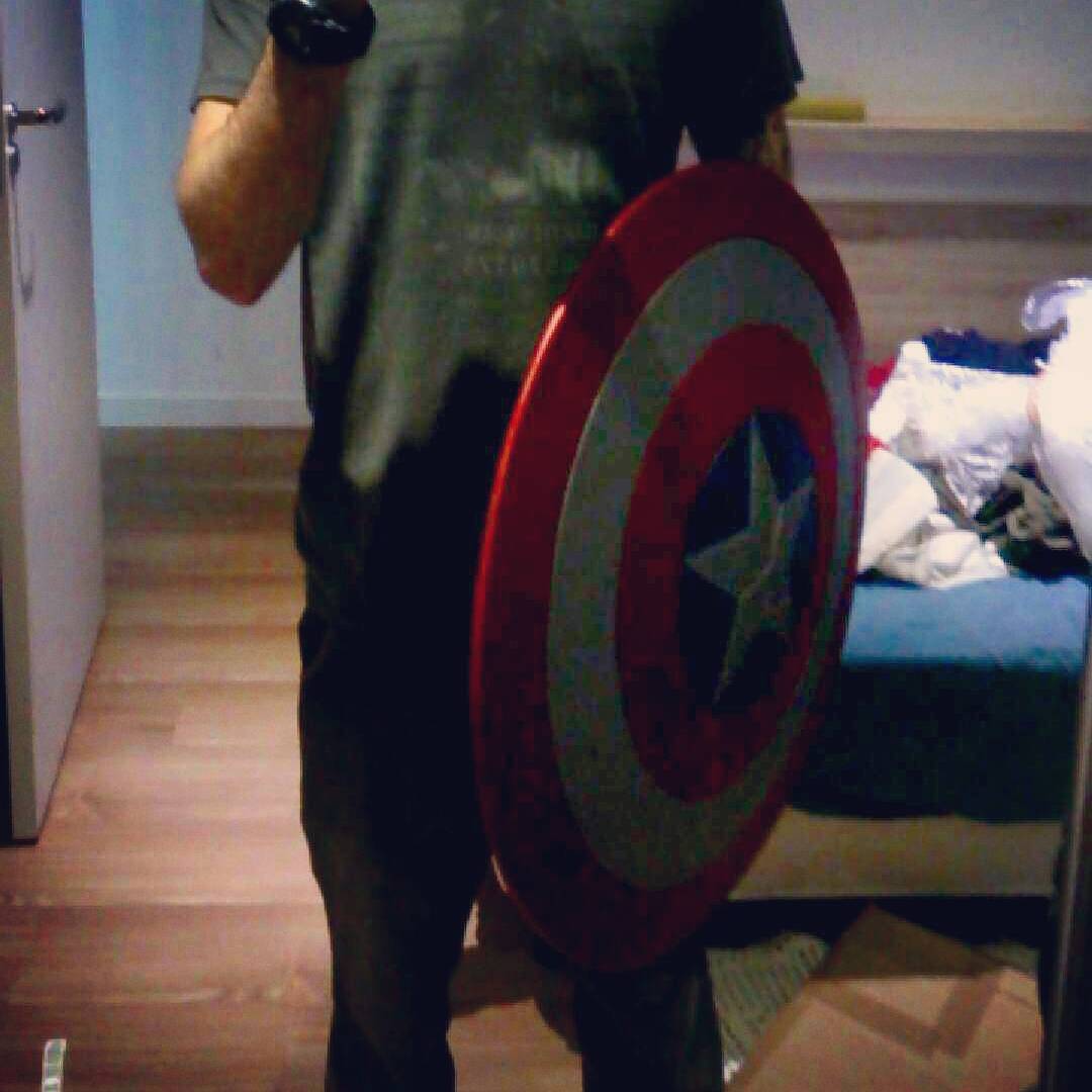 a man is posing for the camera with his captain america shield