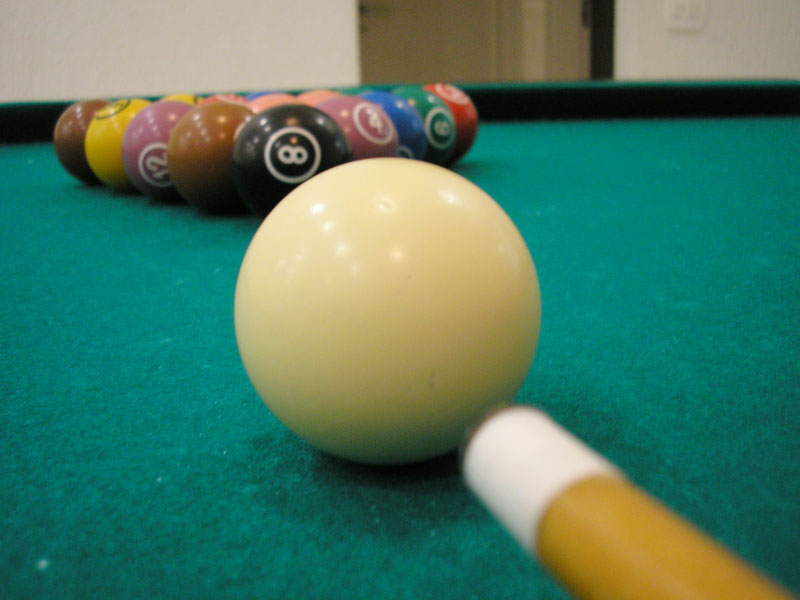 pool balls and a pool stick with an eight ball on a billiard