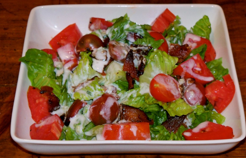 a square bowl with a salad containing lots of vegetables