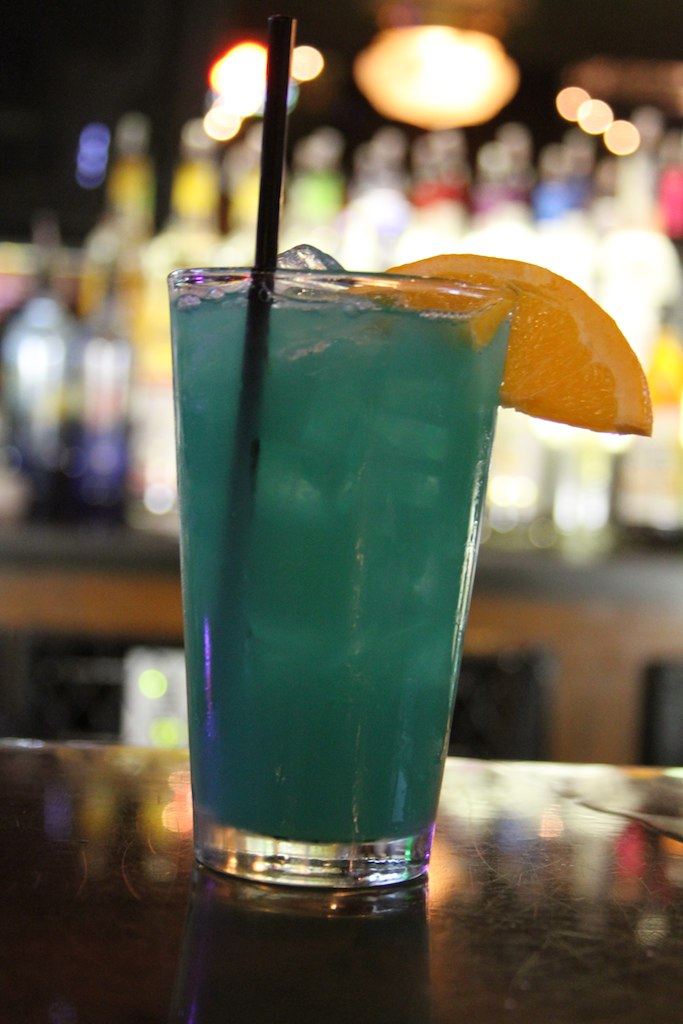 a blue cocktail in a glass on a table