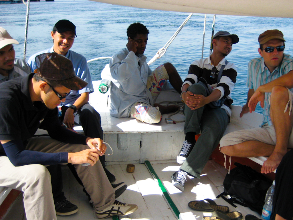 four men sitting on the side of a boat