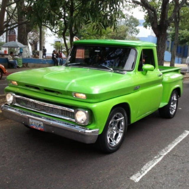 a green pick up truck parked in the parking lot