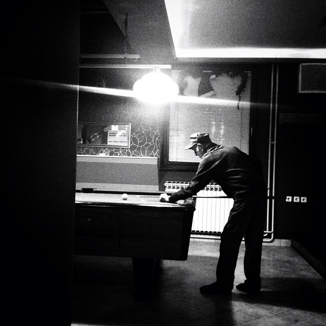 man playing pool at a pool table in the middle of the dark