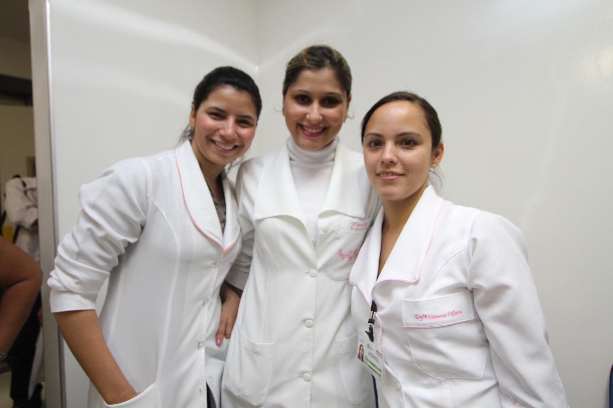 four people wearing white coats smile for the camera