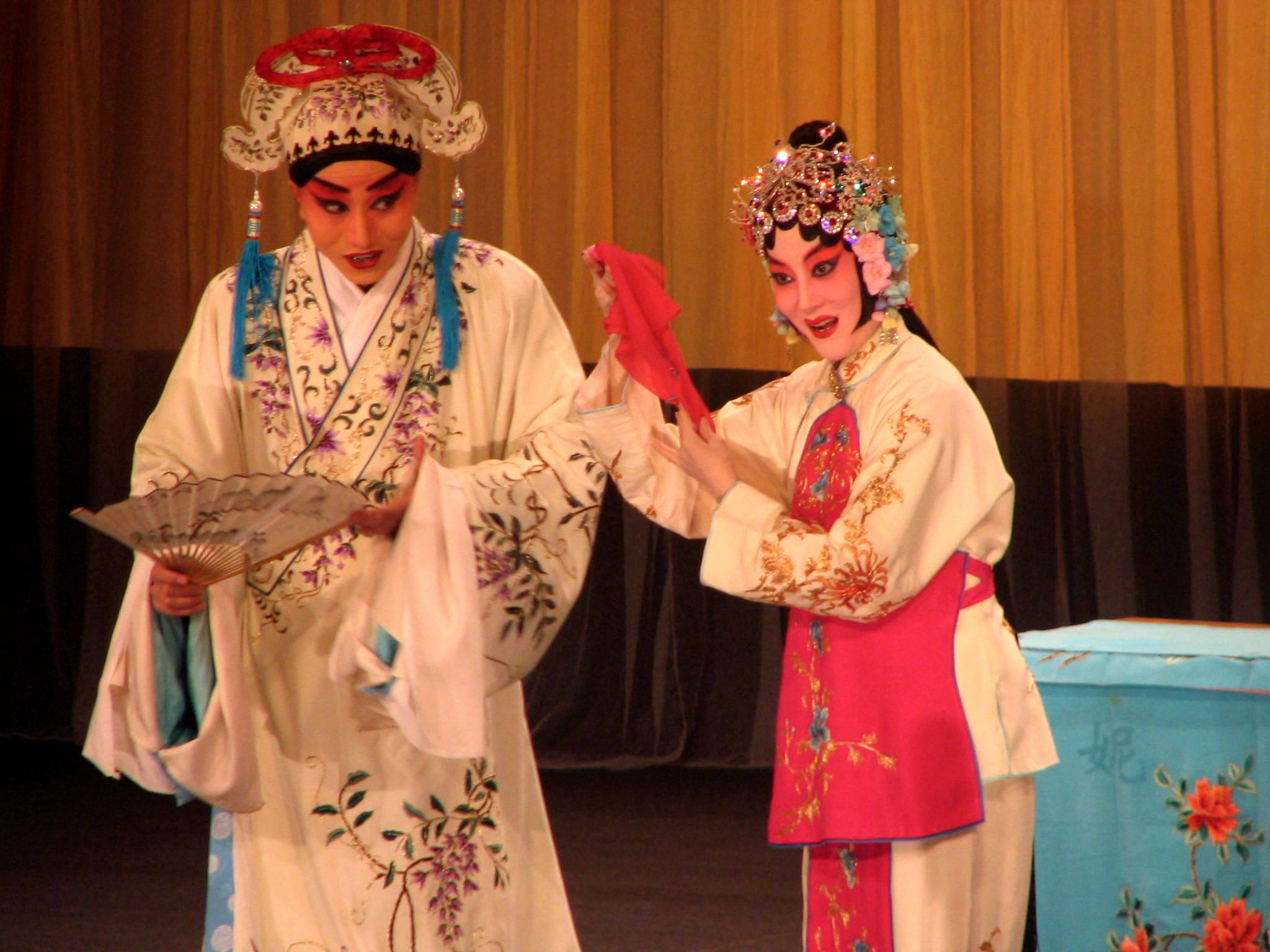 two young people dressed in costumes and headdress, with a large bowl in each hand