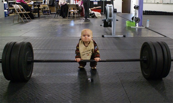 a  who is squatting behind a barbell