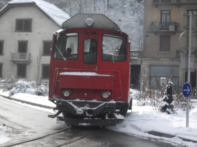 a red train traveling down tracks next to tall buildings