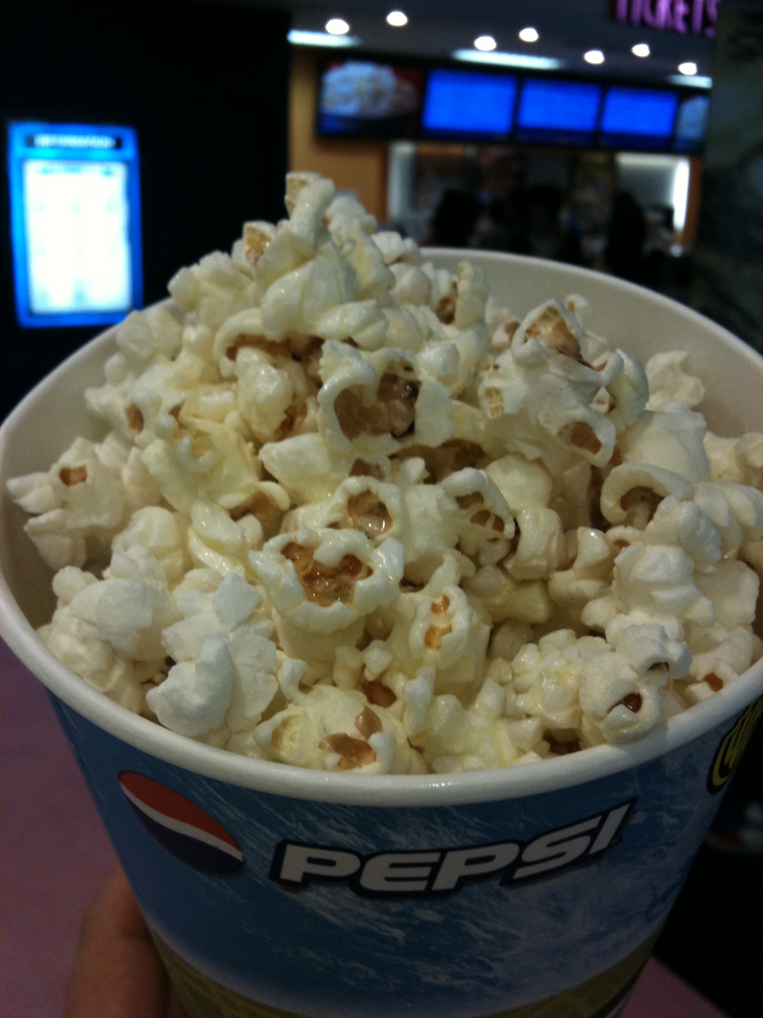 a white cup filled with popcorn sitting next to a screen