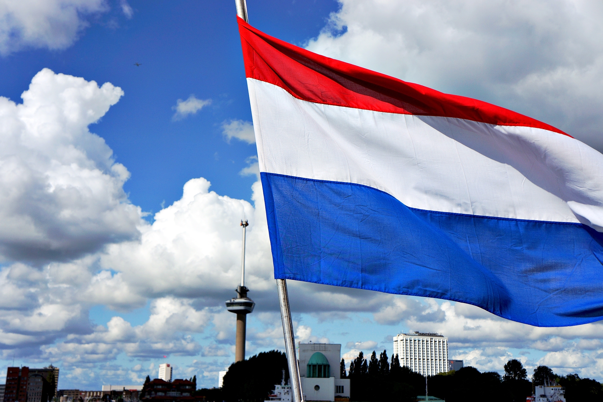 a large flag blowing in the wind with buildings in the background