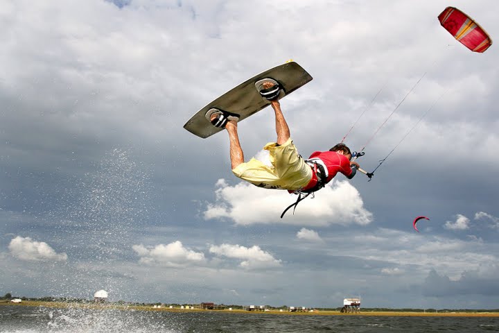 a man is in the air on top of the water while holding onto a board