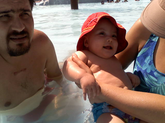 a man holding onto a baby in the water