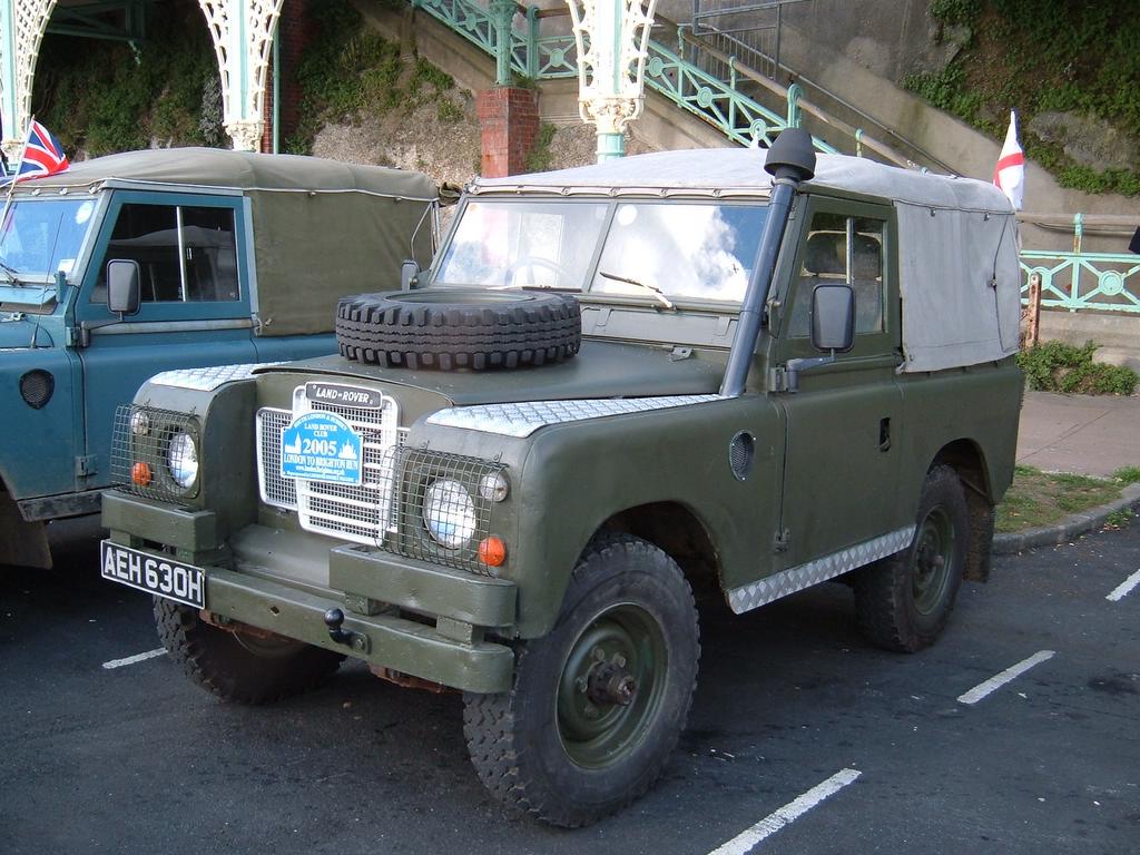 military vehicles parked in a parking lot with a bridge in the background