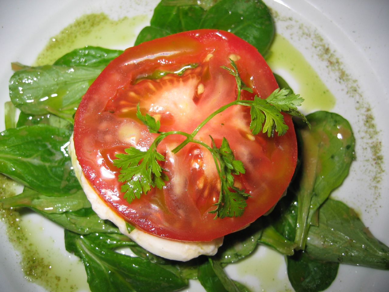 tomato with mozzarella and spinach on top of a plate