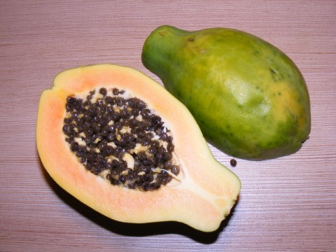 two fruit sitting side by side on top of a wooden table