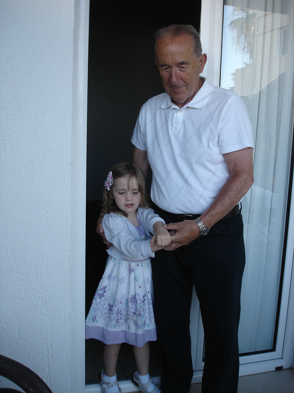 a grandfather and granddaughter standing by the open door