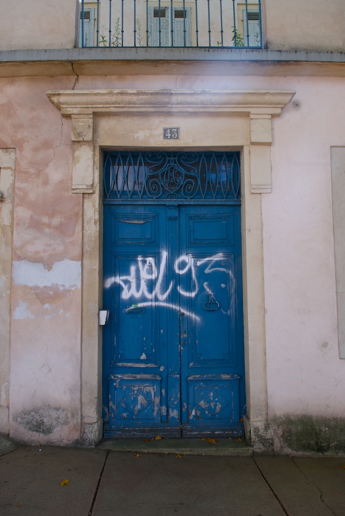 blue double doors are covered with white spray paint