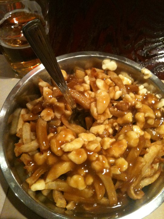 a pan filled with noodles sitting next to a glass of beer