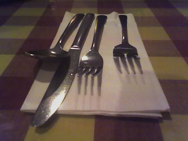 there are forks, knives and spoons sitting on a napkin