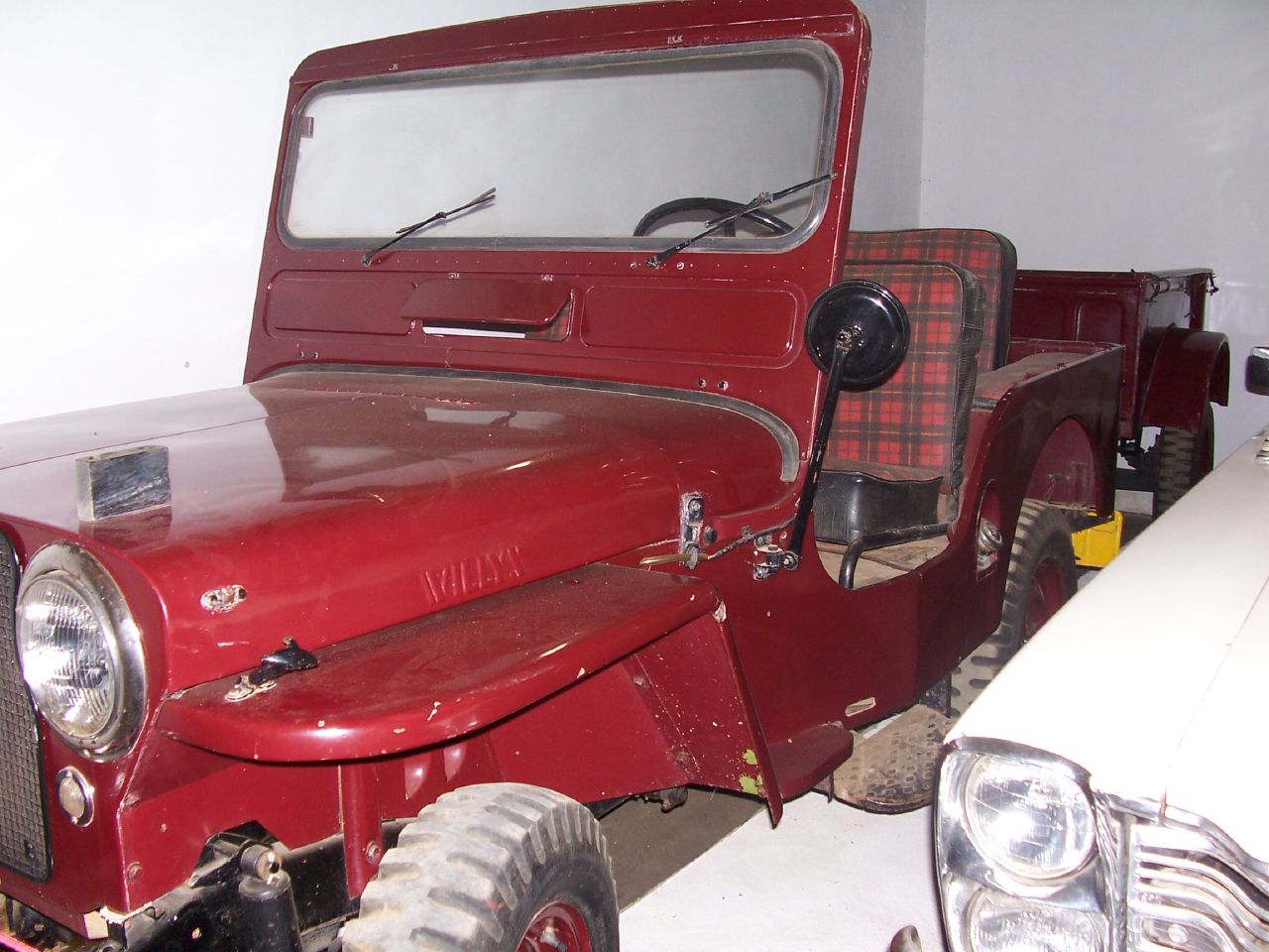 an old red jeep is sitting in the garage