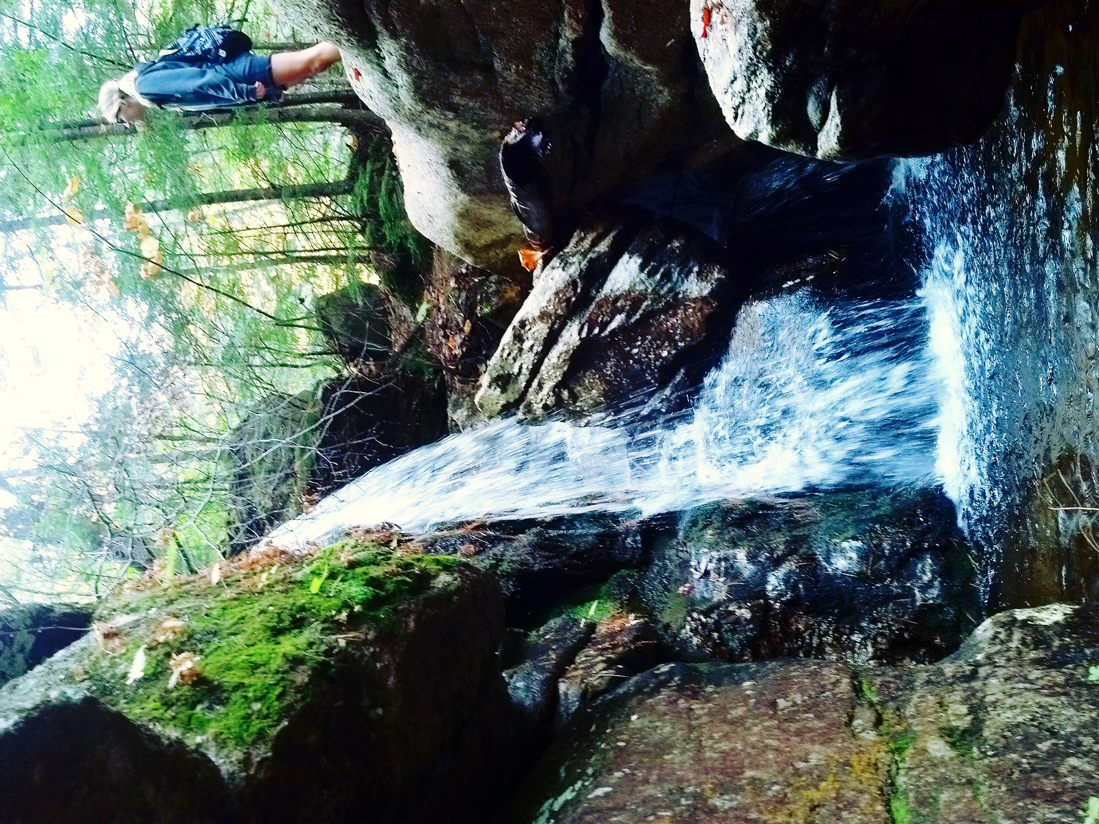 a woman looks at a small waterfall on a rock