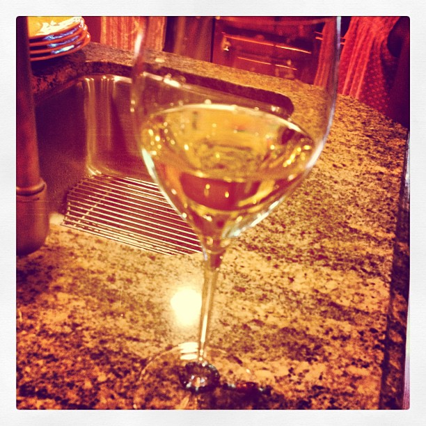 a half filled glass of white wine sitting on a counter