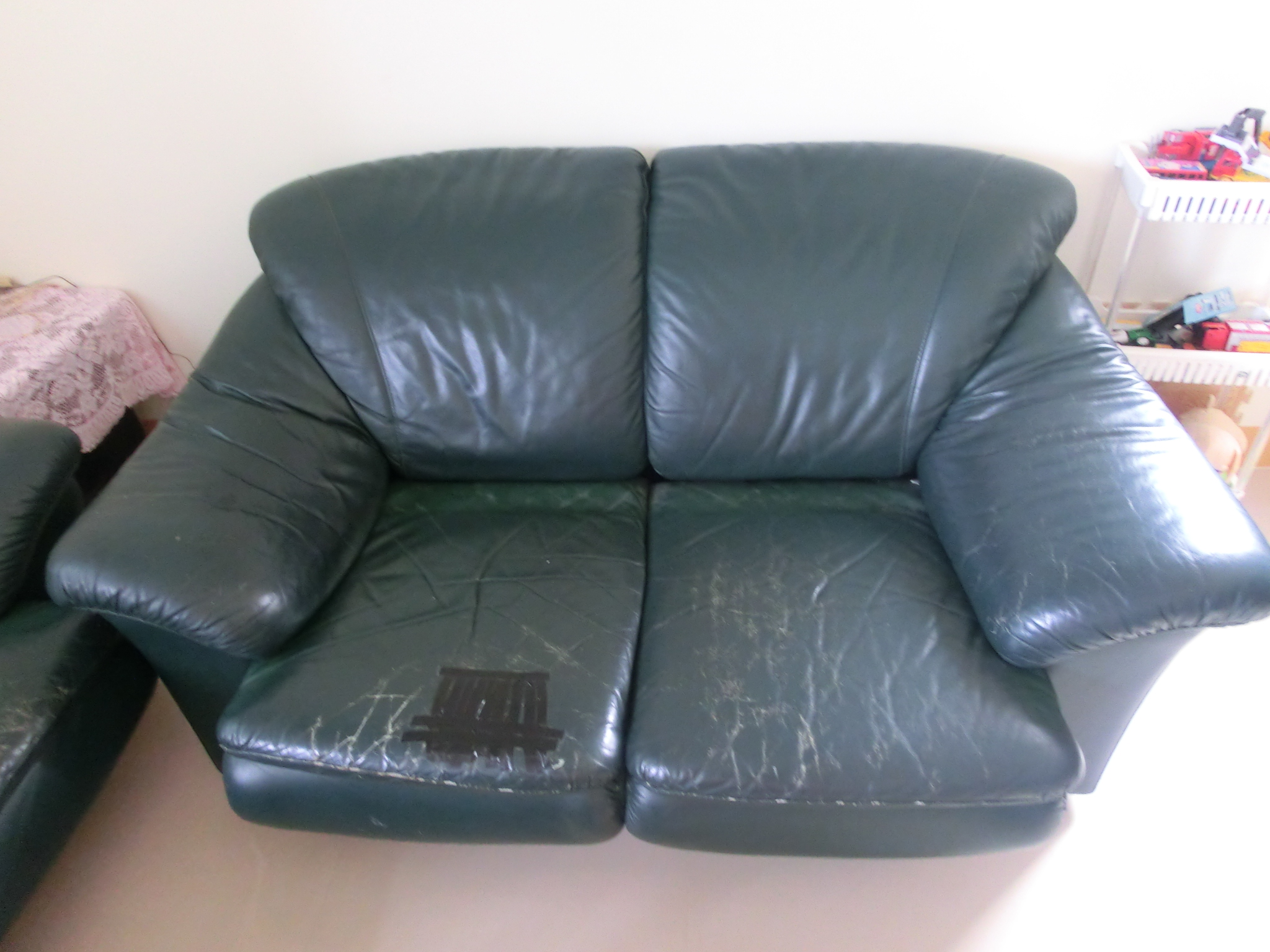 green leather couch and footstool next to wall
