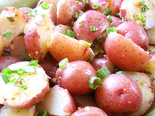 red potatoes are tossed in a pan with a dressing