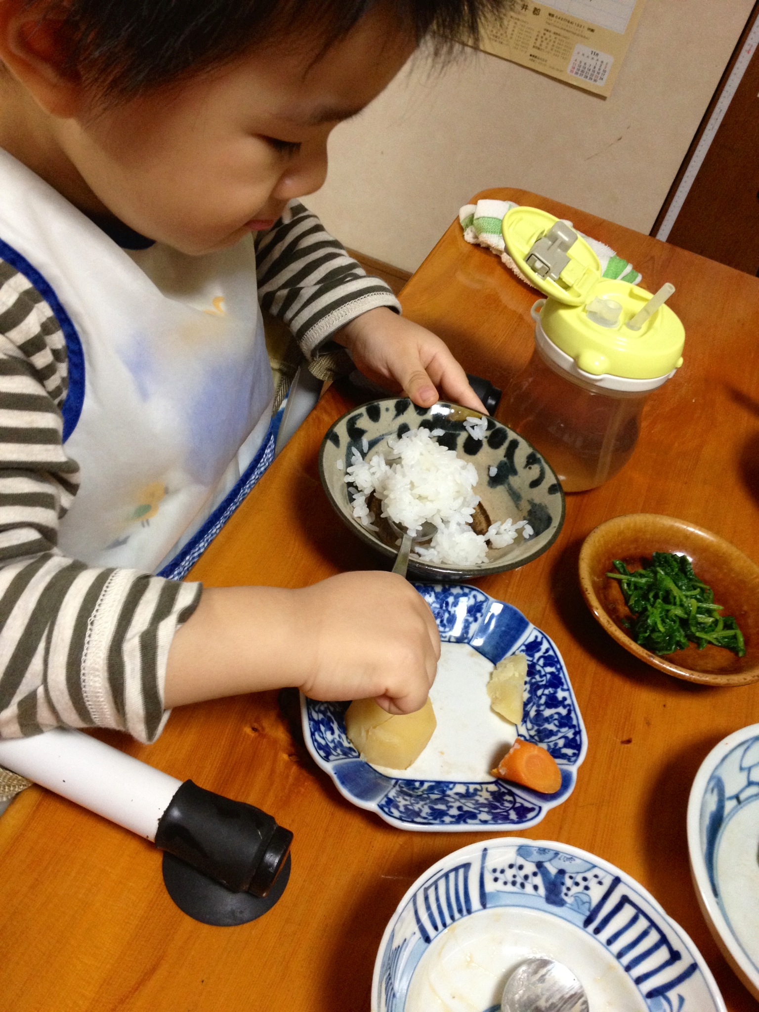 a boy at the table eats rice and vegetables with his spoon