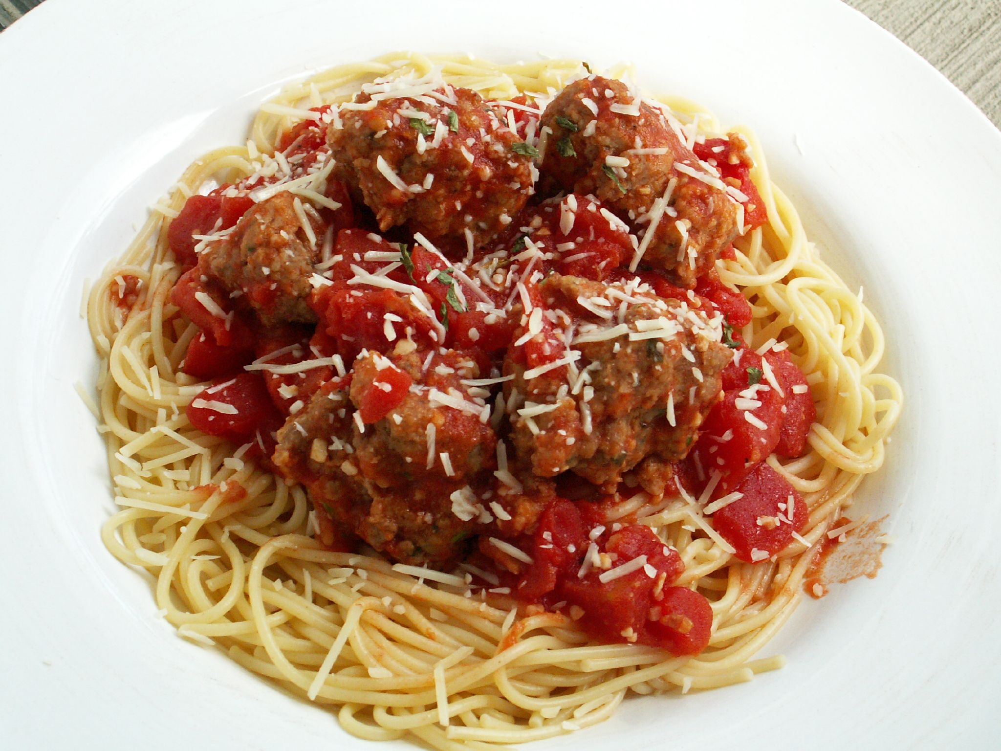 spaghetti with meatballs and marinara sauce in a white bowl